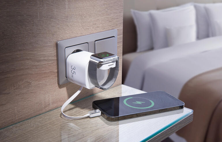 Schnellladegerät, das ein Smartphone und eine Smartwatch gleichzeitig auflädt, in einer Hotelumgebung.
