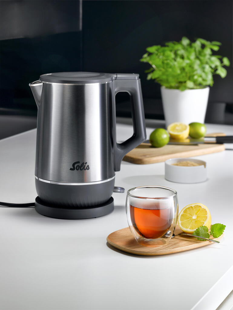 Doppelw. Wasserkocher mit Edelstahl-Finish und Tee in Glasschale auf Tisch.