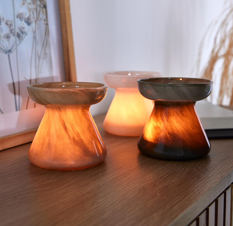 Drei stilvolle, leuchtende Glasvasen auf einem Tisch