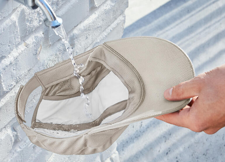 Beige Kühlkappe, von Hand unter Wasser gehalten, während Wasser herausfließt