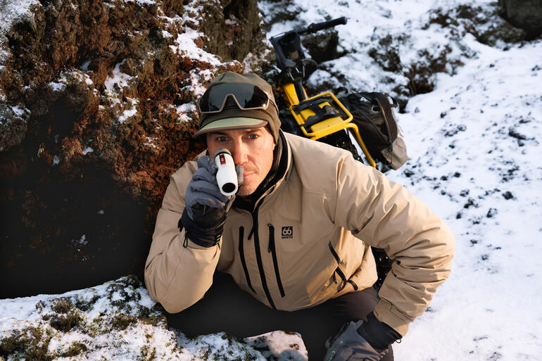 Mann beobachtet mit einem Monokular in den Bergen während des Schnees.