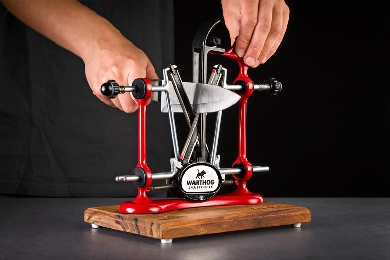 Profi-Messerschärfer in rot wird von einer Hand genutzt.