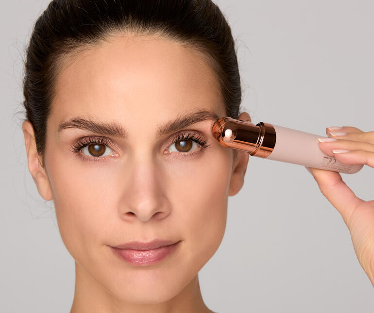 Frau hält Gesichtsrasierer Roxy an ihre Augenbraue.