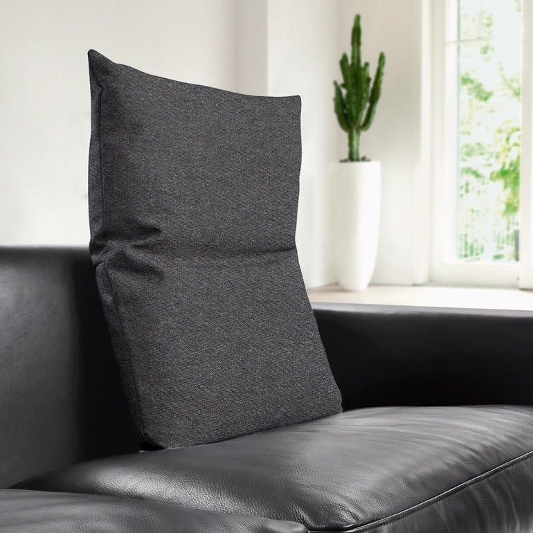 Frau mit braunem Rückenkissen auf einer weißen Couch.