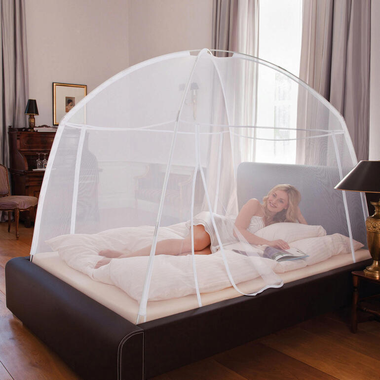 Mobiles Moskitonetz über einem Bett, mit einer Person darin.