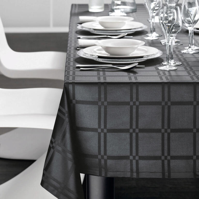 Fleckabweisende Tischdecke in Schwarz, dekoriert mit Geschirr und Gläsern auf einem Tisch.