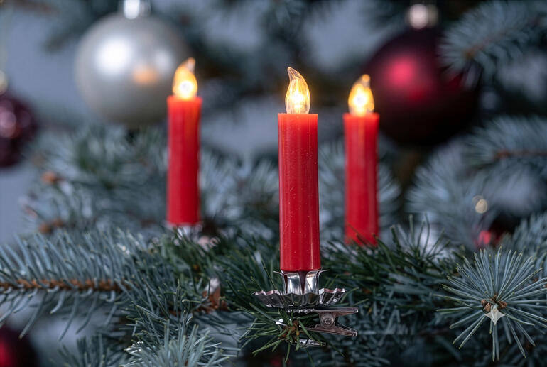 Rote LED Echtwachs-Christbaumkerzen an einem Weihnachtsbaum.
