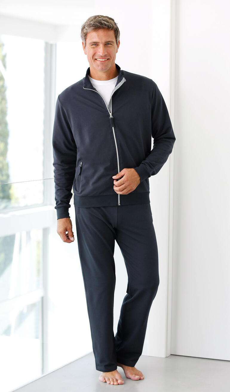 Mann in einem dunkelblauen Coolmax-Fitnessanzug, lächelt und steht barfuß.