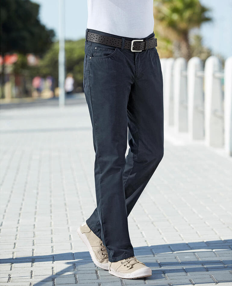 Dunkelblau Mann geht in Coolmax® Sommer-Five-Pocket-Hosen auf einem Gehweg.