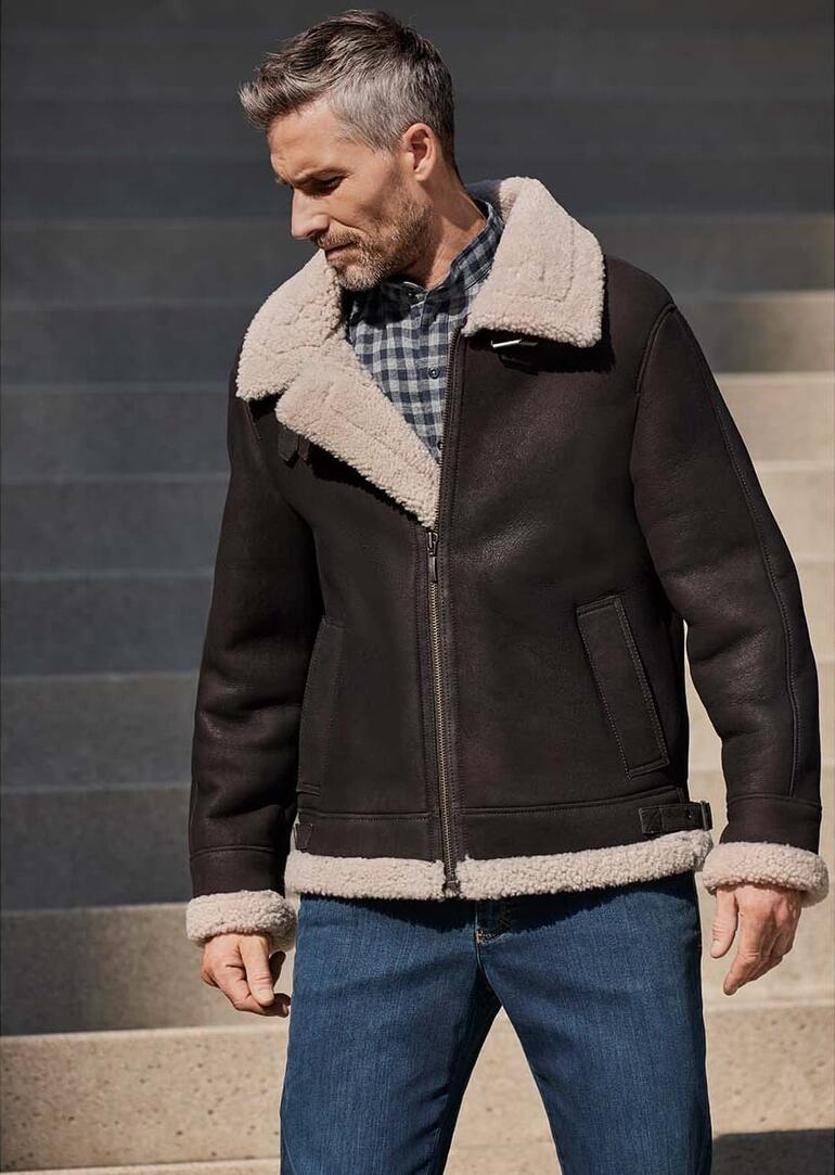 Mann trägt eine Lammfell-Fliegerjacke B3, stehend auf Treppen.