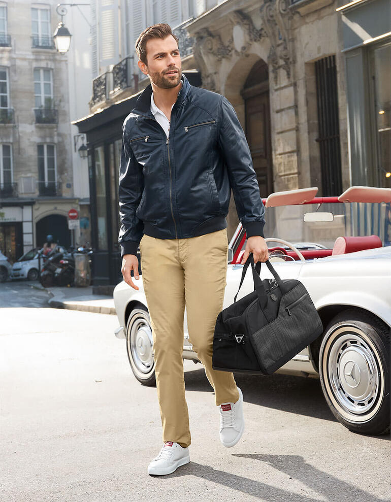 Mann trägt blauen Sommer-Lederblouson und beige Hose auf der Straße.