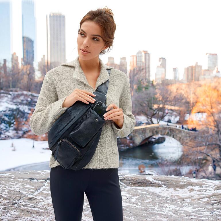 Frau mit Anokhi Crossbody-Bag in winterlicher Umgebung mit Brücke im Hintergrund.