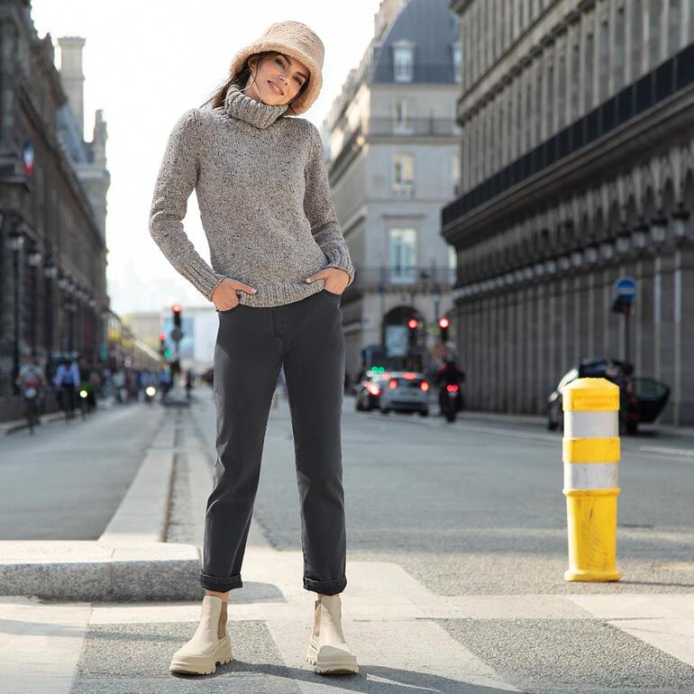 Frau in grauem Pullover und bucket hat auf der Straße.