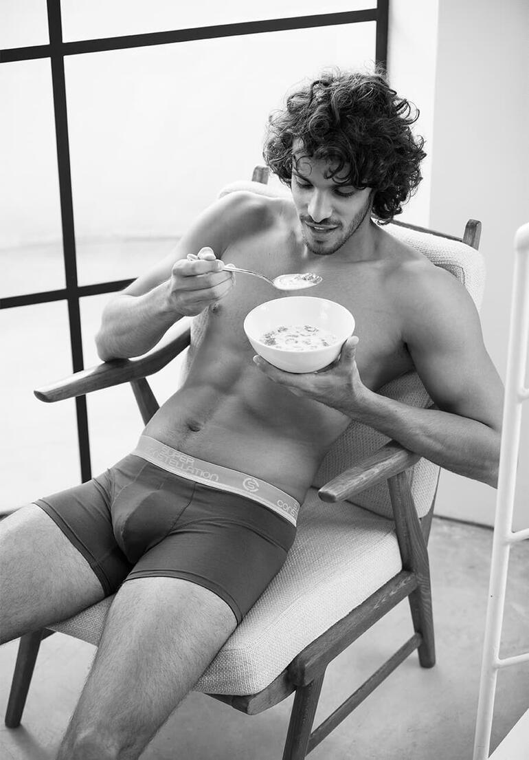 Mann in Boxershorts, frühstückt mit einer Schüssel Müsli.