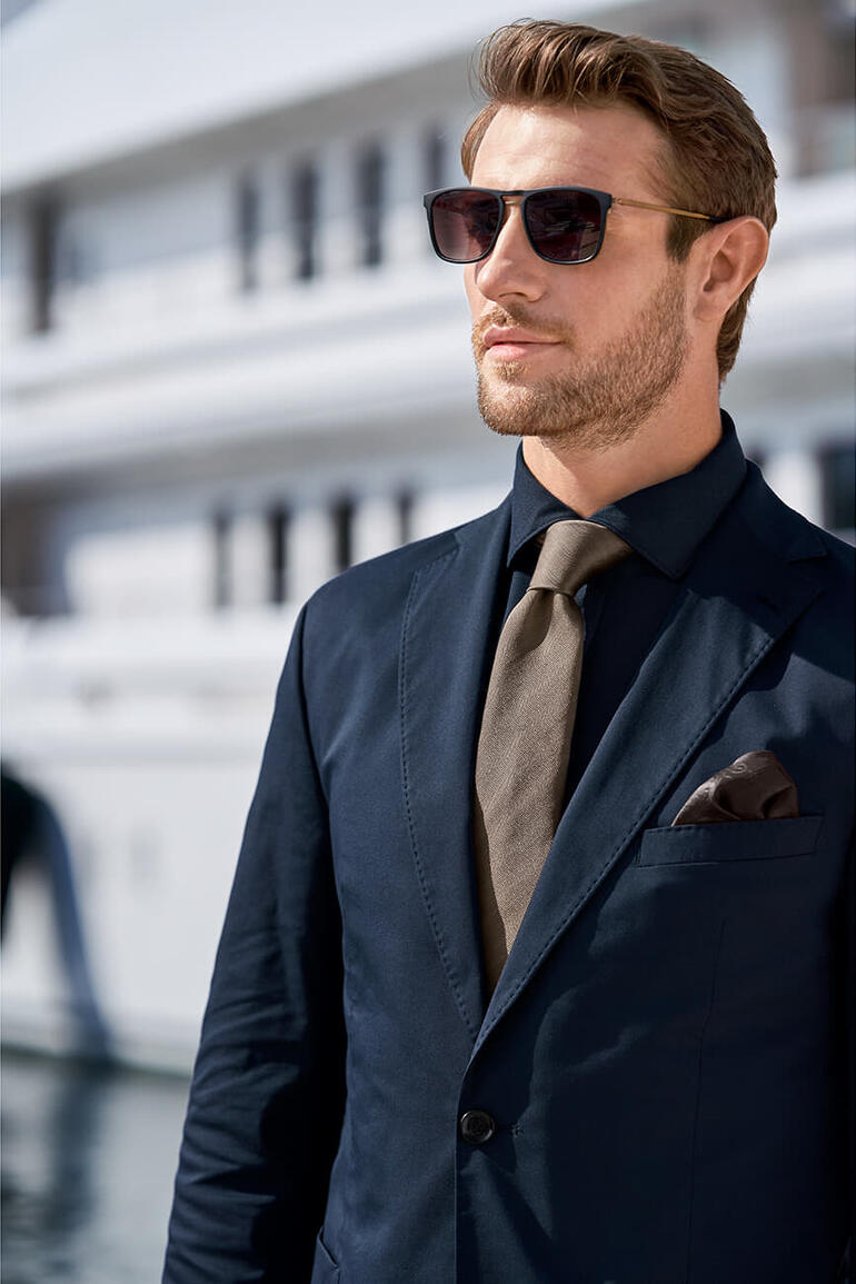 Mann in Anzug mit dunkeloliver Krawatte und Sonnenbrille.
