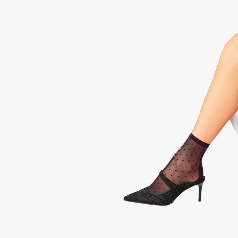 Schwarze Punkte-Söckchen aus Nylon, an einem Fuß getragen.
