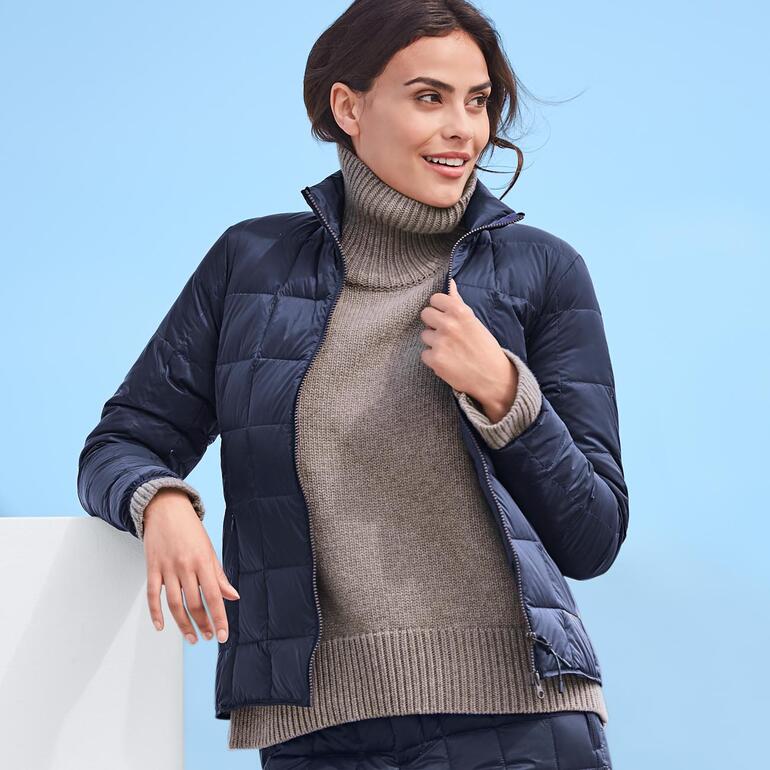 Frau trägt eine navy Daunenjacke mit einem Rollkragenpullover.