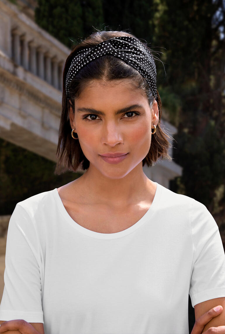 Frau trägt Roeckl Seiden-Stirnband mit Punkten, schaut in die Kamera.