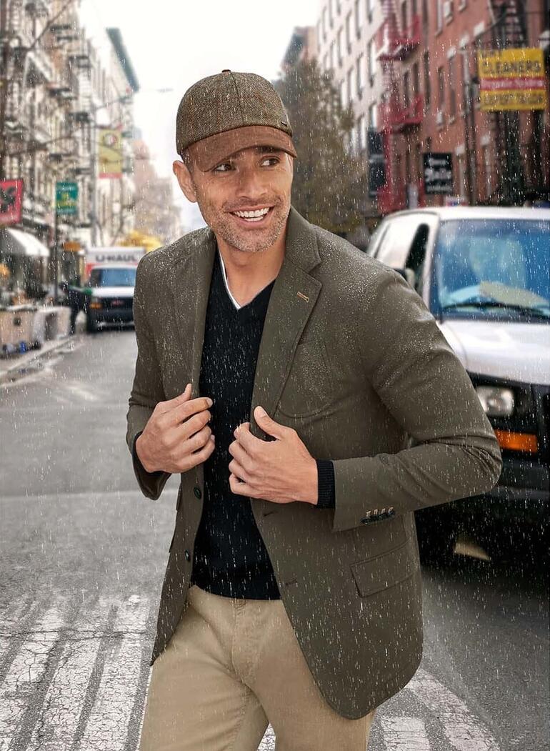 Mann in Allround-Blazer, der im Regen lächelt, Stadtumgebung.