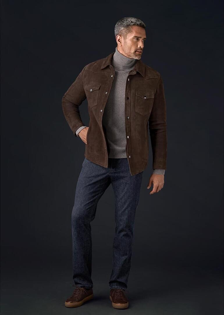 Mann trägt ein Lammfell-Overshirt von OCONI und steht auf einem Sanddünenweg.