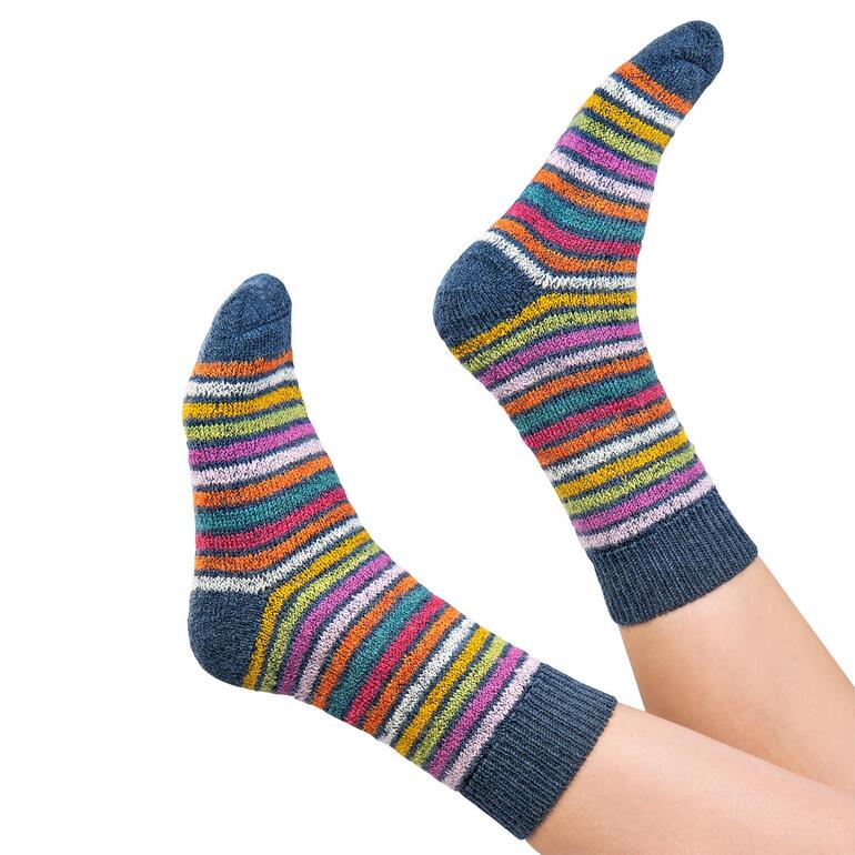 Paar Regenbogen-Ringelsocken in Blau/Rot an den Füßen.