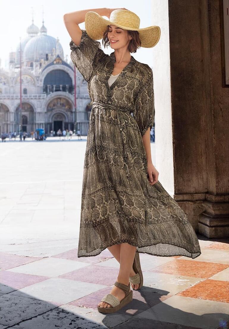 Taupe Frau in einem langen, gemusterten Kleid und Strohhut in Venedig.