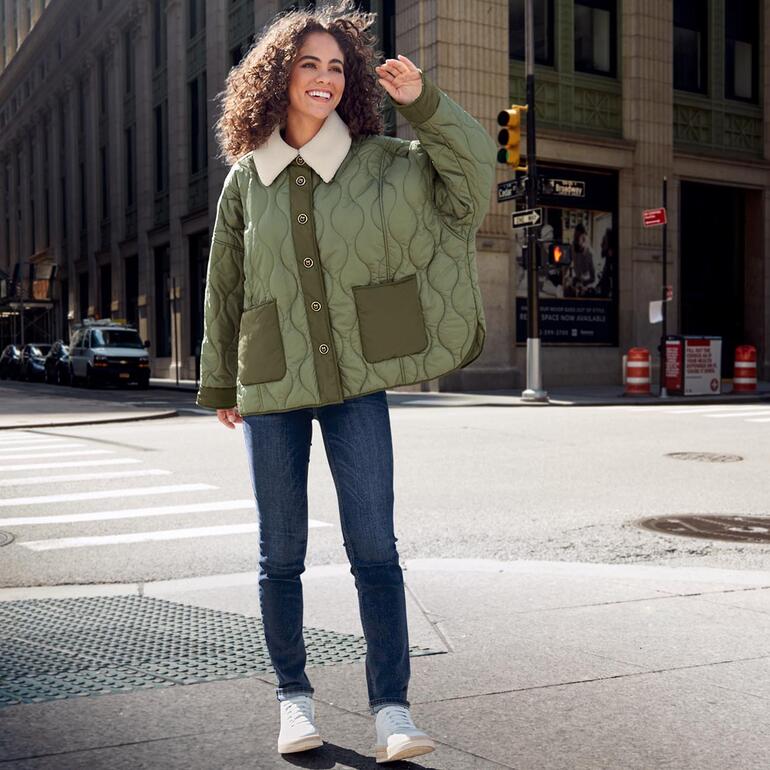 Frau trägt Vintage-Sneaker mit heller Jacke auf der Straße.