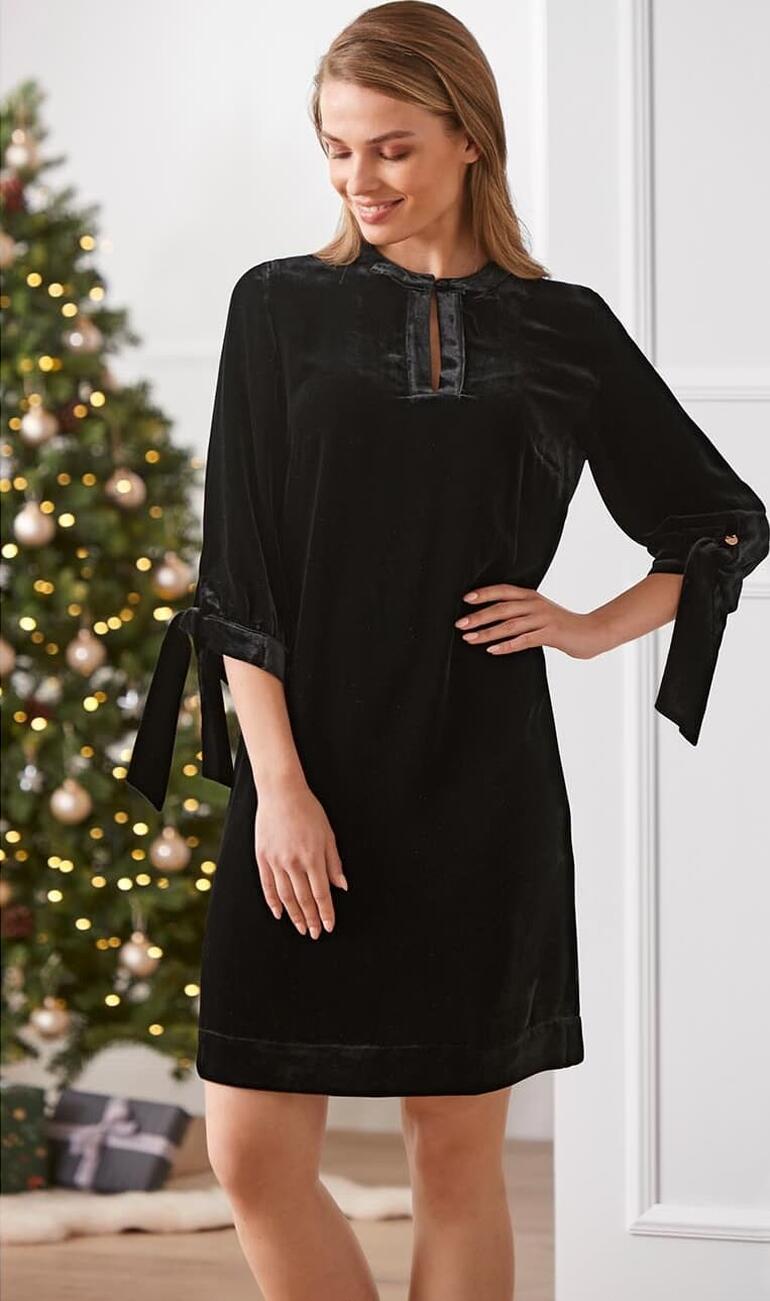 Damen-Tunika-Kleid aus Seidensamt in schwarz mit Schleifenärmeln, Weihnachtsdeko im Hintergrund.