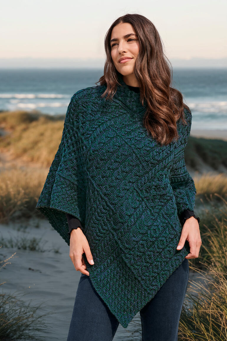 Bleu atlantique Frau im Aran-Poncho posiert am Strand.