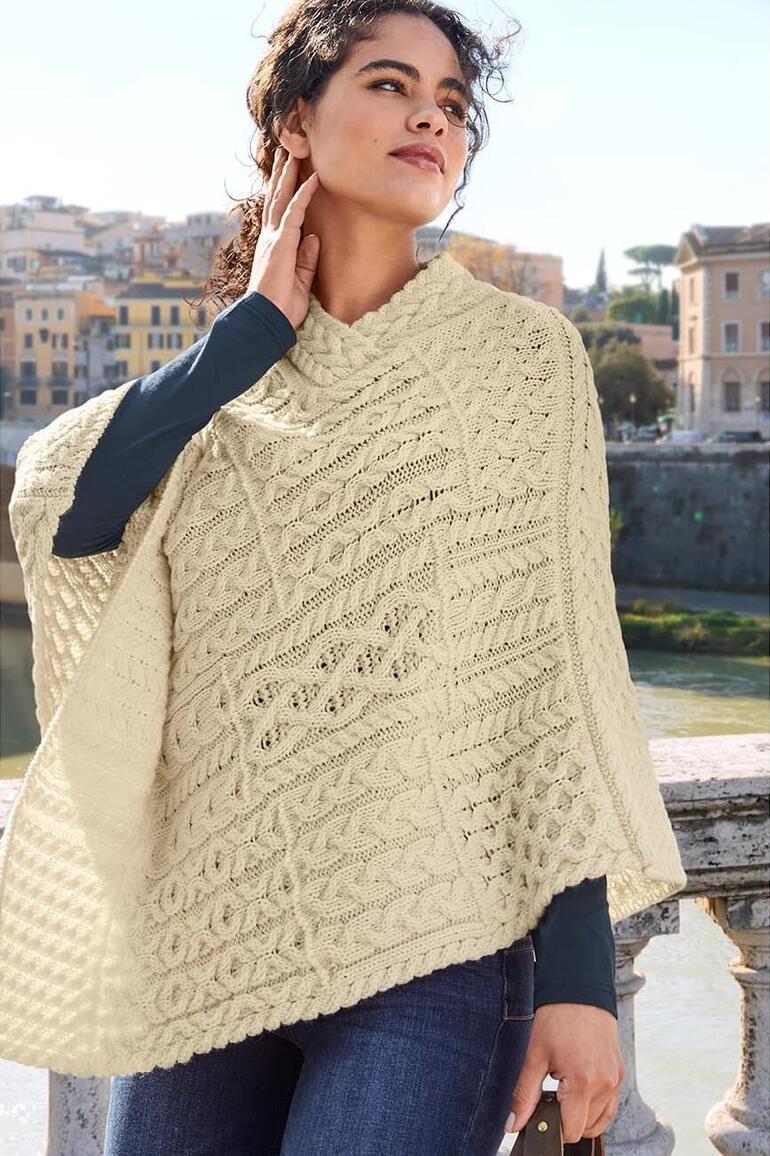 Frau in hellem Poncho auf einer Brücke mit verblassten Jeans.