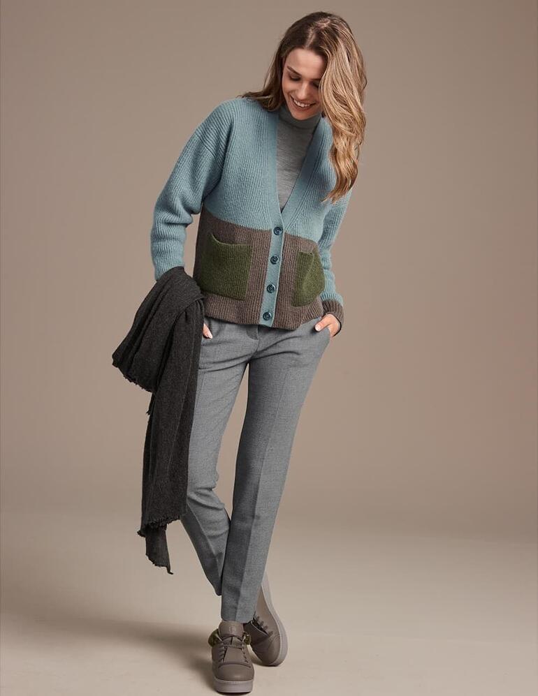 Frau in grünem Cardigan mit Chaaya Lammfell-Sneakern auf braunem Hintergrund.