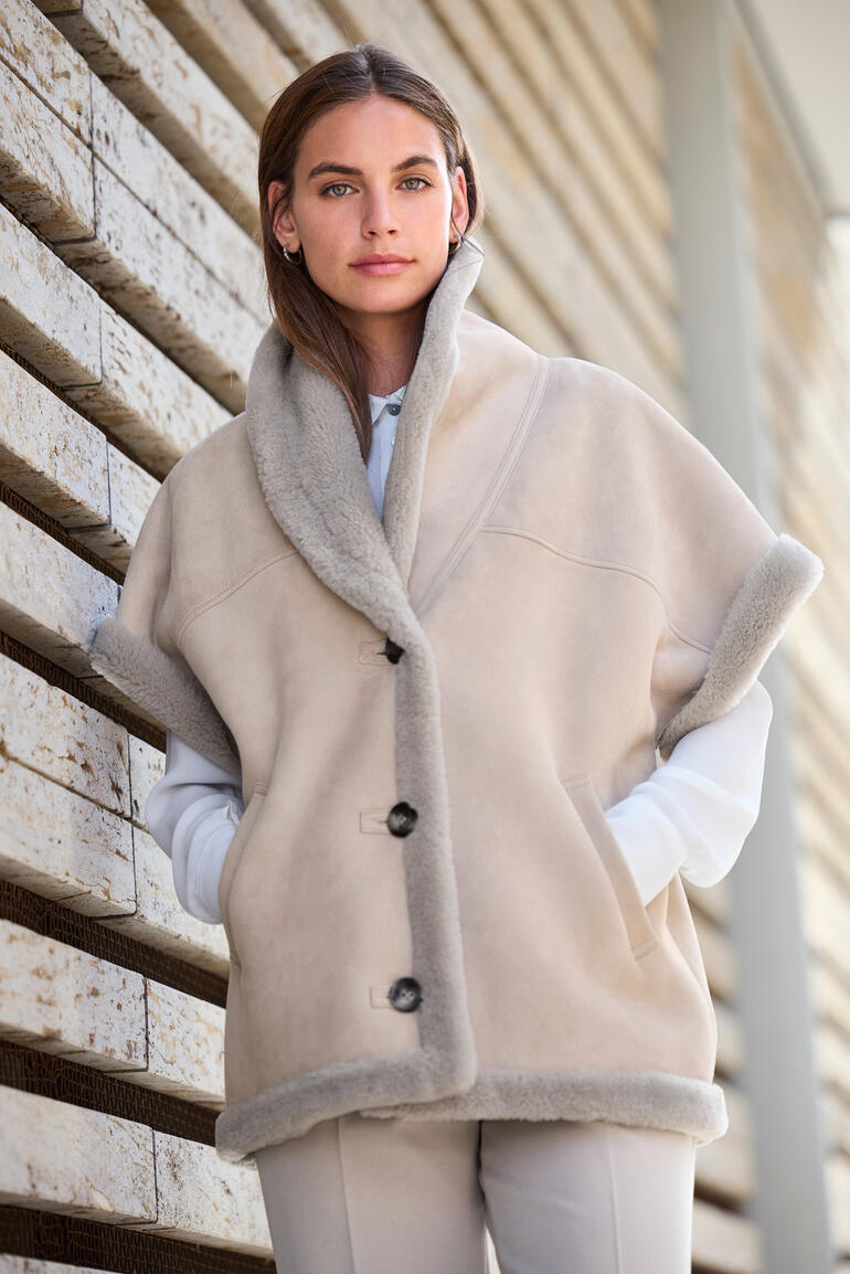 Beige Lammfell-Weste mit aufgestellten Kragen, getragen von einer Frau.