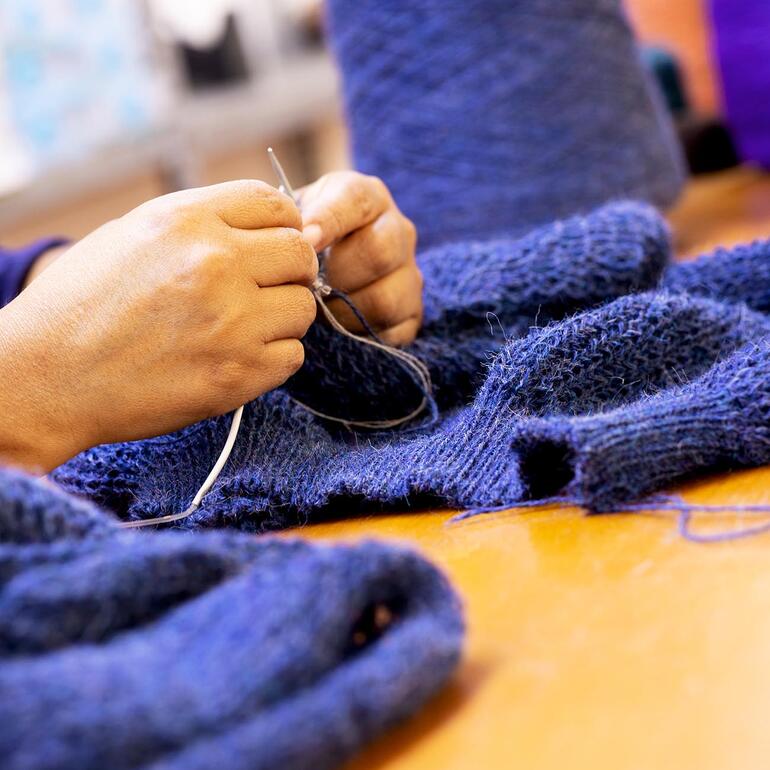 Hände beim Nähen eines Alpaka-Honeycomb-Pullovers