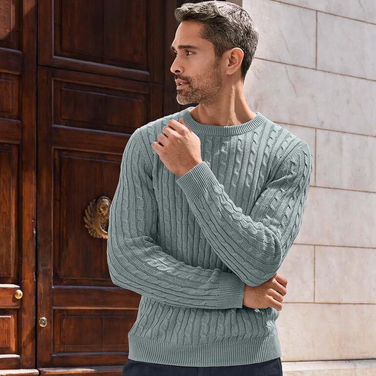 Nahaufnahme von Mann in Carbery Leinen-Zopfpullover in einer urbanen Umgebung.