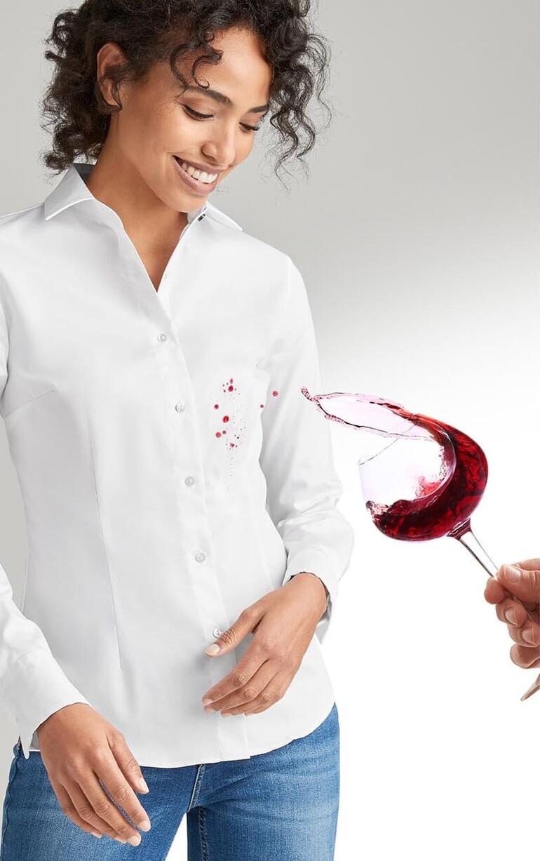 Lachenende Frau in weißer QuickClean-Bluse, wird mit Rotwein bespritzt.