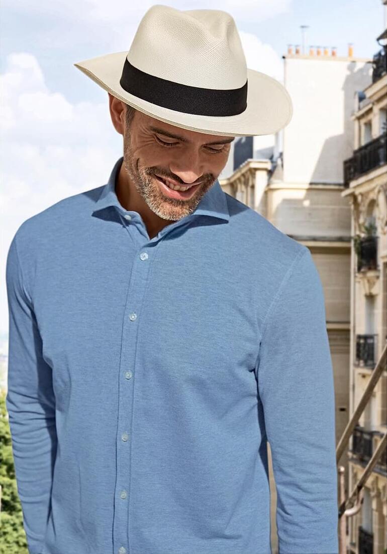 Mann mit Panama-Hut und hellblauem Shirt.