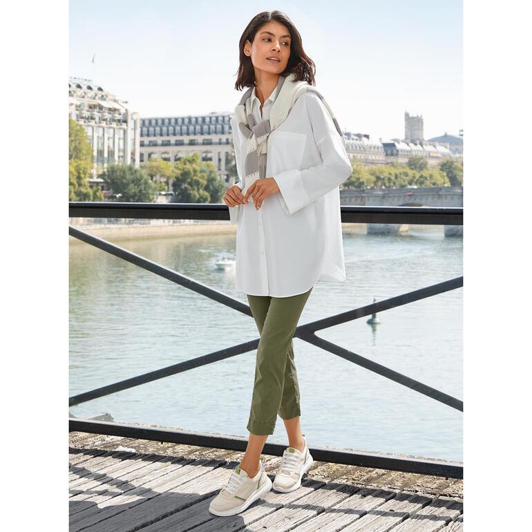 Frau in Oversize-Sommerbluse am Flussufer.
