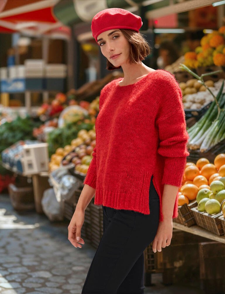 Frau trägt roten Alpaka-Wohlfühlpulli auf einem Marktplatz