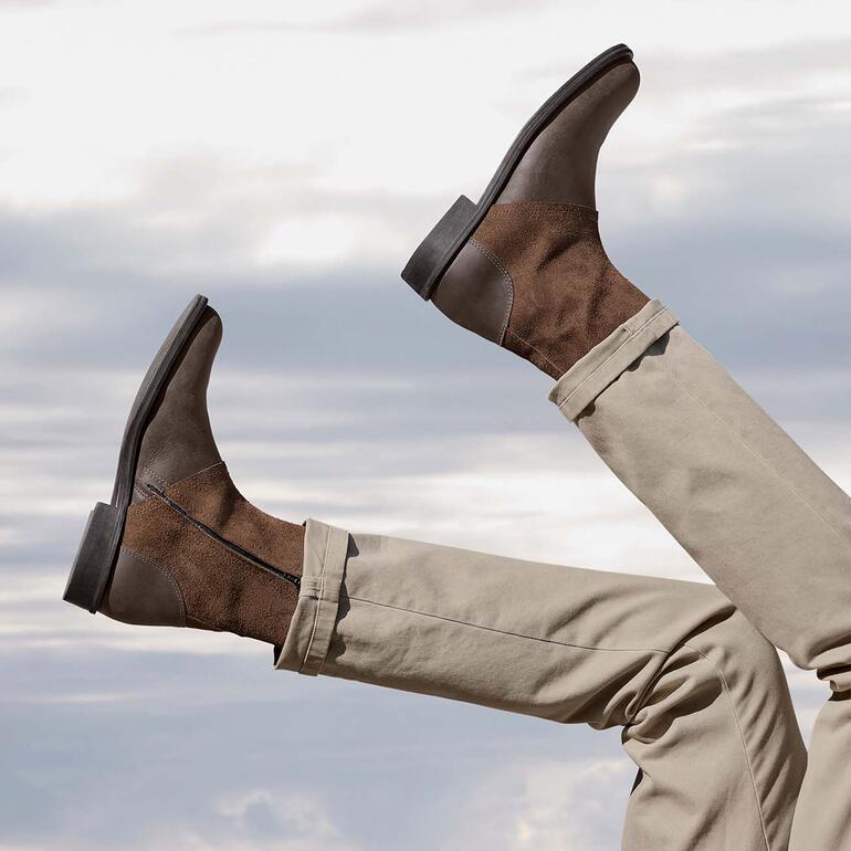 Turduli Büffelleder-Boots Braune Büffelleder-Boots, die mit den Füßen in die Luft gehalten werden