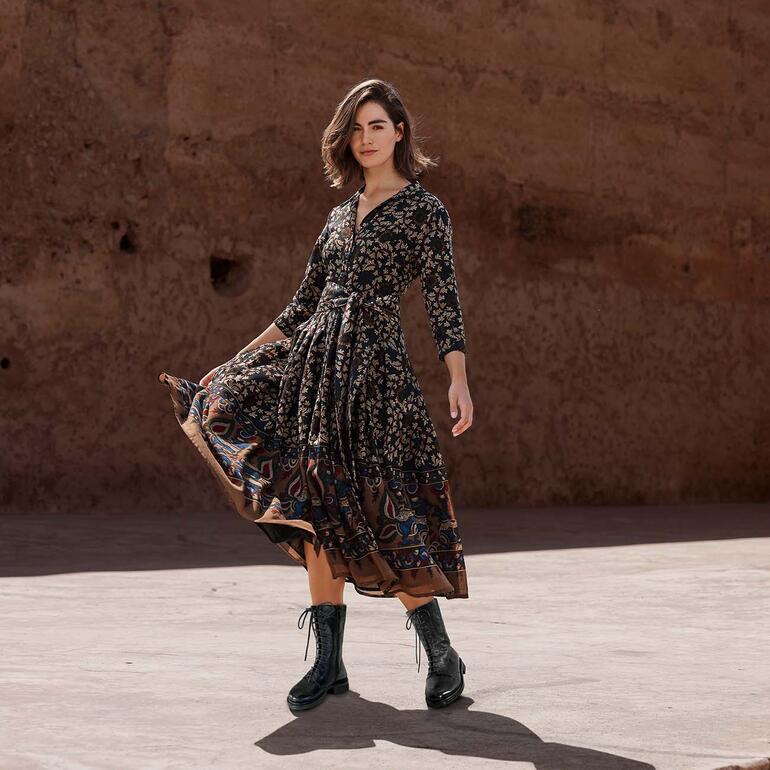 Cordwainer Schnürboots Dame in Wollkleid mit Blumenmuster, die einen Schwung in der Bewegung ausführt.