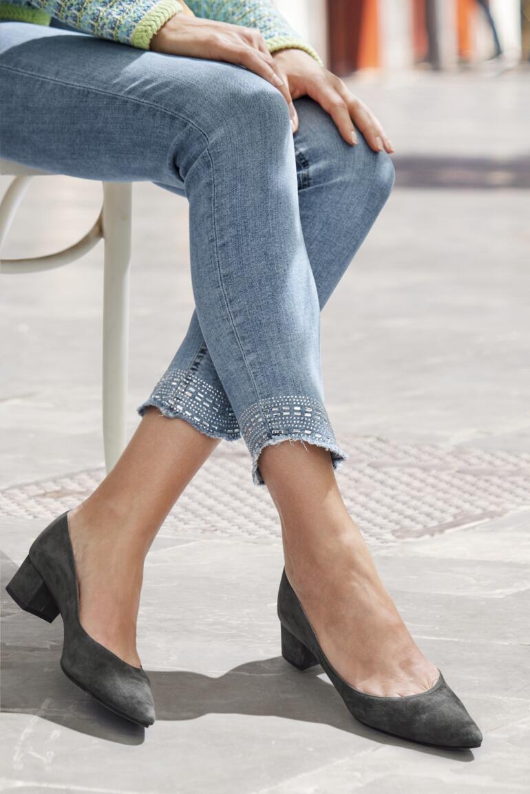 Frau mit grauen Schuhen trägt zerrissene Jeans.