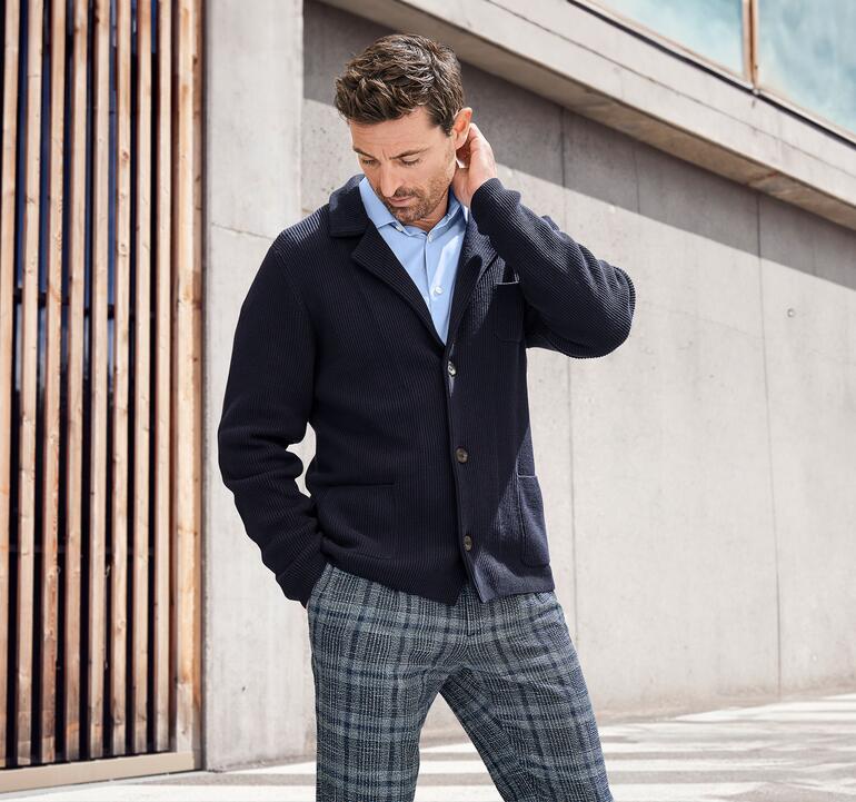 Mann in Pima-Rippstrick-Sakko betrachtet nachdenklich seine Kleidung.