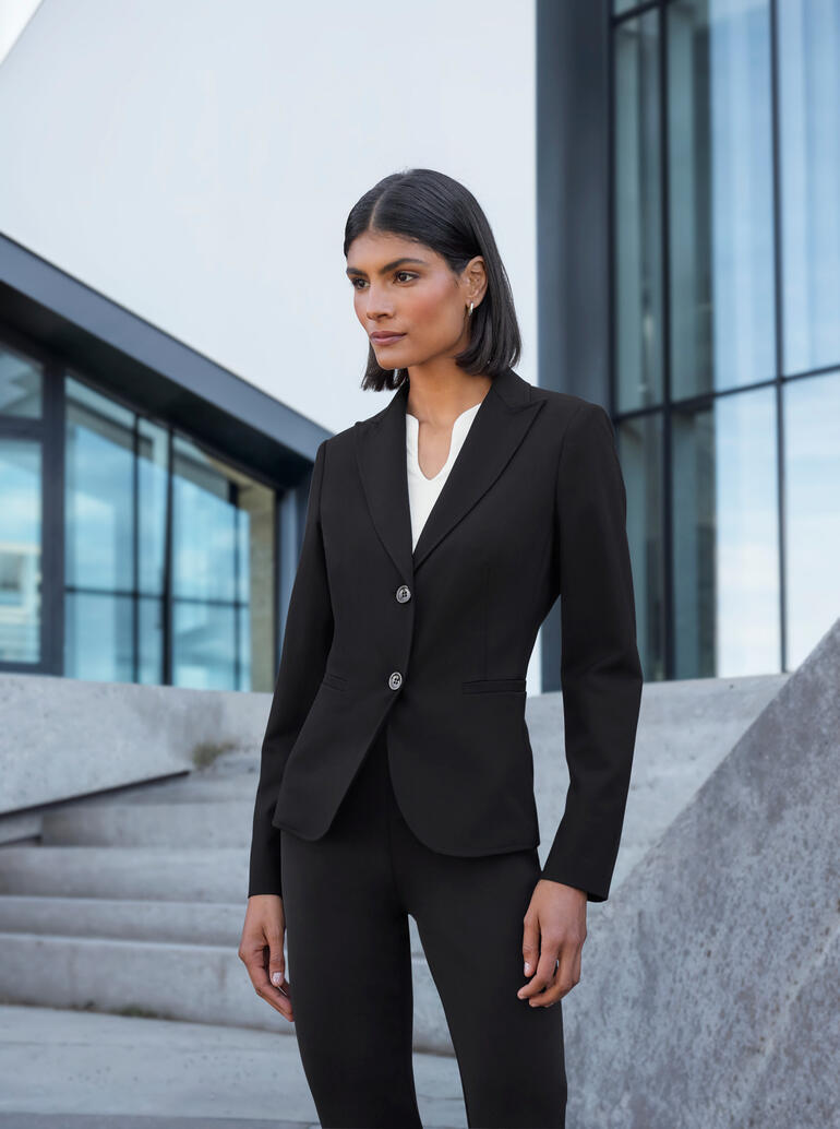 Frau in eleganter Blazer-Kombination vor modernen Gebäuden