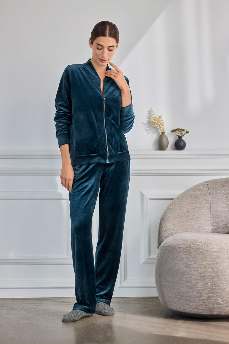 Frau trägt grünen Hanro Loungewear-Samt-Anzug, entspannt in moderner Umgebung.