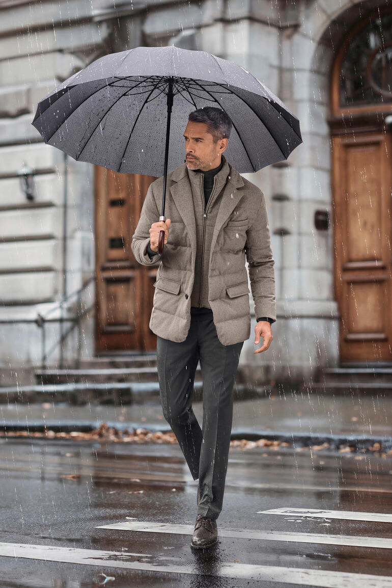 Lodenfrey Kaschmir-Daunenjacke Mann mit Lodenfrey Kaschmir-Daunenjacke unter einem Regenschirm