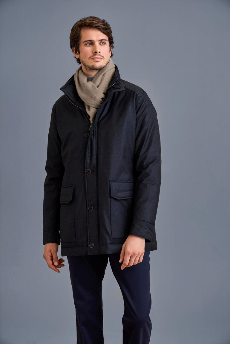 Lodenfrey Storm System®-Jacke Mann in Lodenfrey Storm System®-Jacke mit Schal vor grauem Hintergrund.