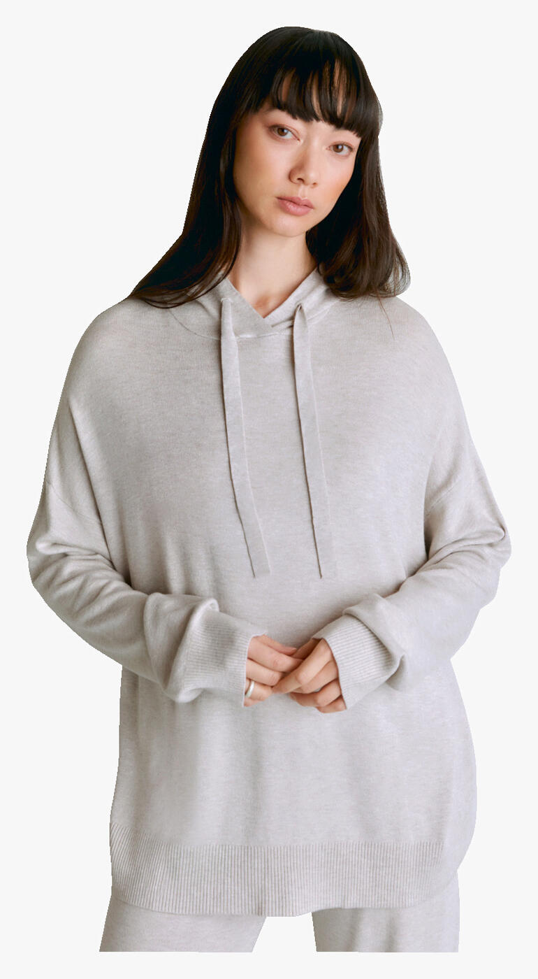Frau in hellgrauem Lyocell/Kaschmir-Hoodie mit Kapuze auf weißem Hintergrund.