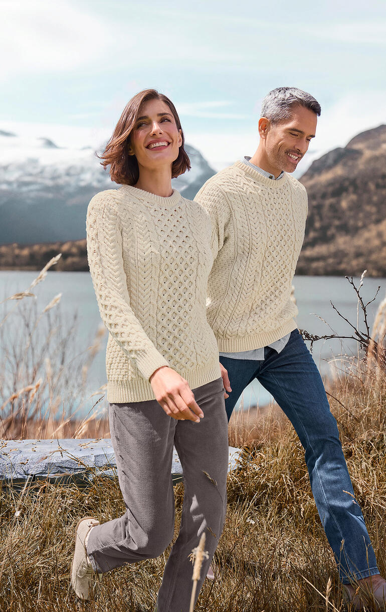 Paar in Merino-Aran-Pullis bei einem Spaziergang mit Naturhintergrund
