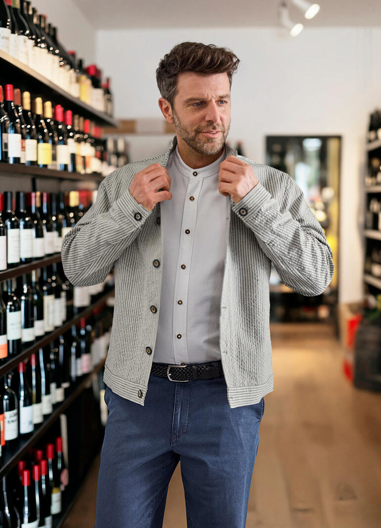 Mann zieht Leinen-Seersucker-Janker in einem Weinladen an.