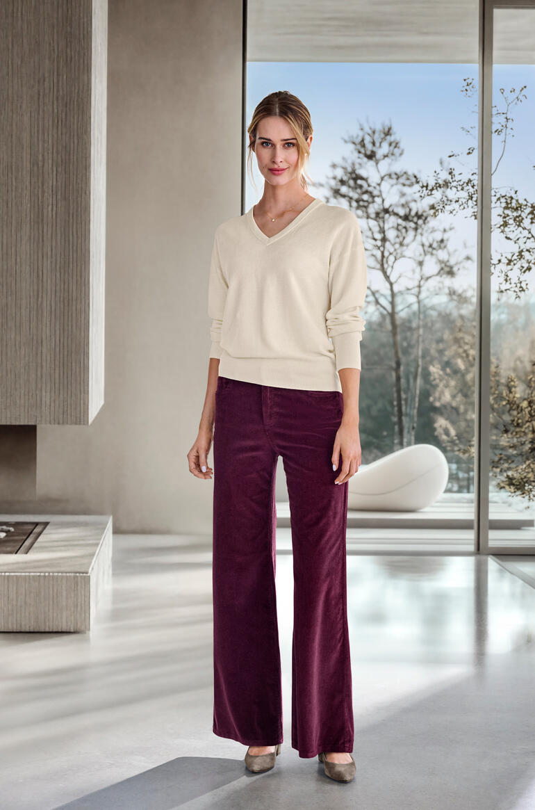 Frau mit weit geschnittener Cordhose in Bordeaux und V-Pullover